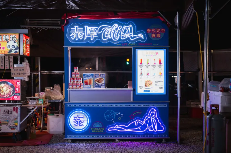 夜裡的泰厚 CHILL 攤車全景,招牌、菜單燈箱、泰字章與側躺女子霓虹都亮著