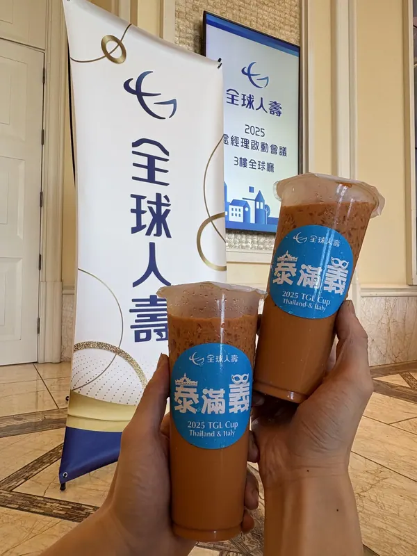 兩杯貼著客製杯貼的泰式奶茶,背後是活動旗幟