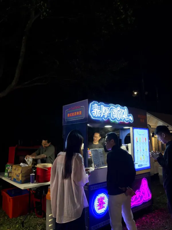 賓客站在攤車前,師傅在霓虹燈下現場沖泰式奶茶