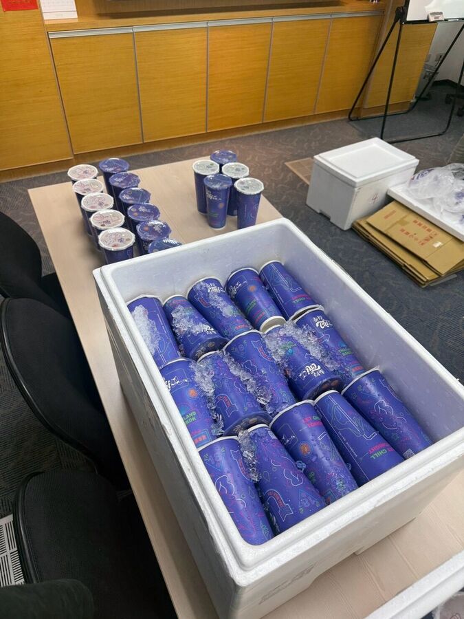 桌上一箱封膜奶茶，旁邊散放著幾杯