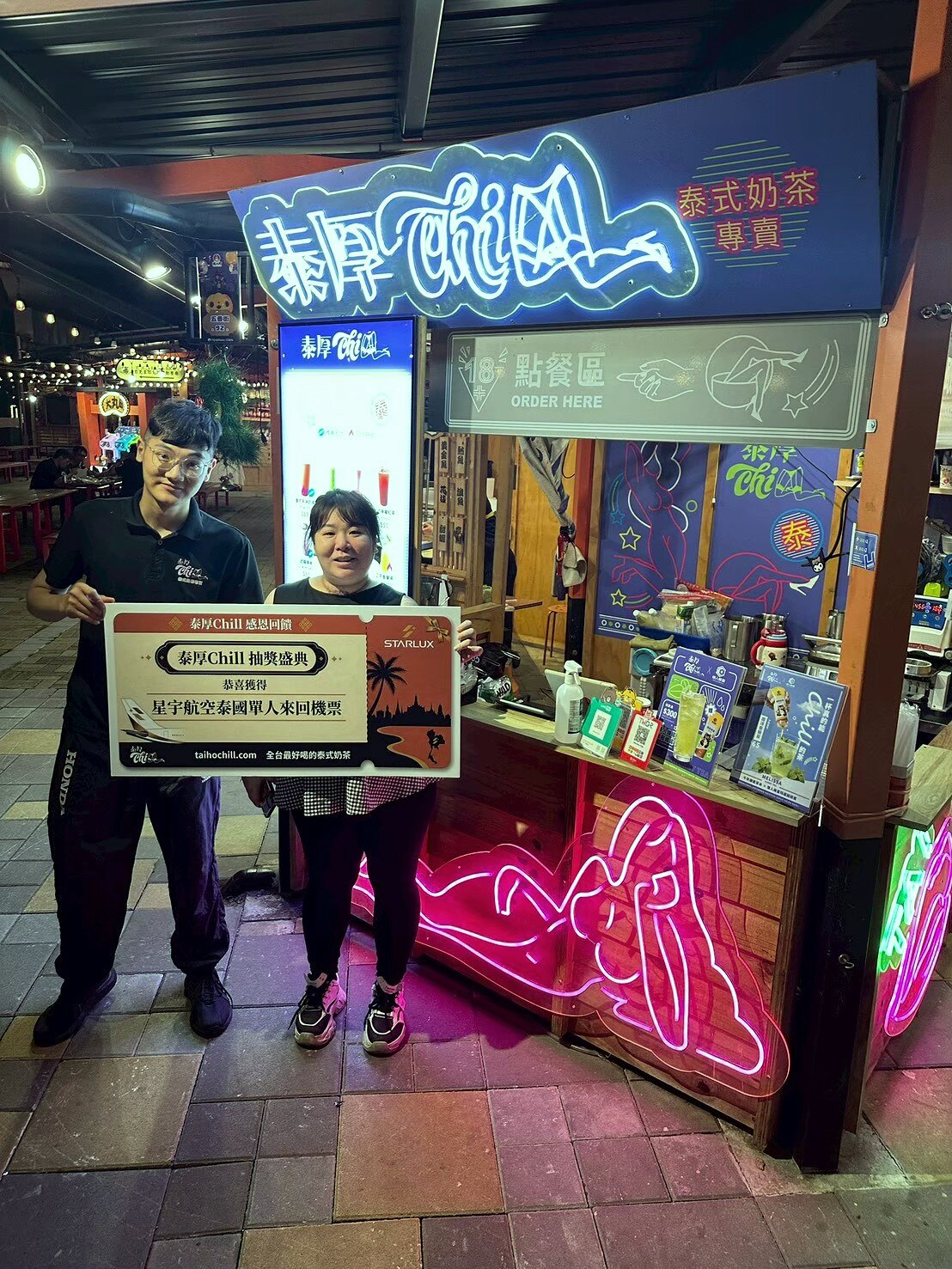 漁人町旗艦店點餐區前，得主與店員手持星宇航空泰國機票獎牌合影