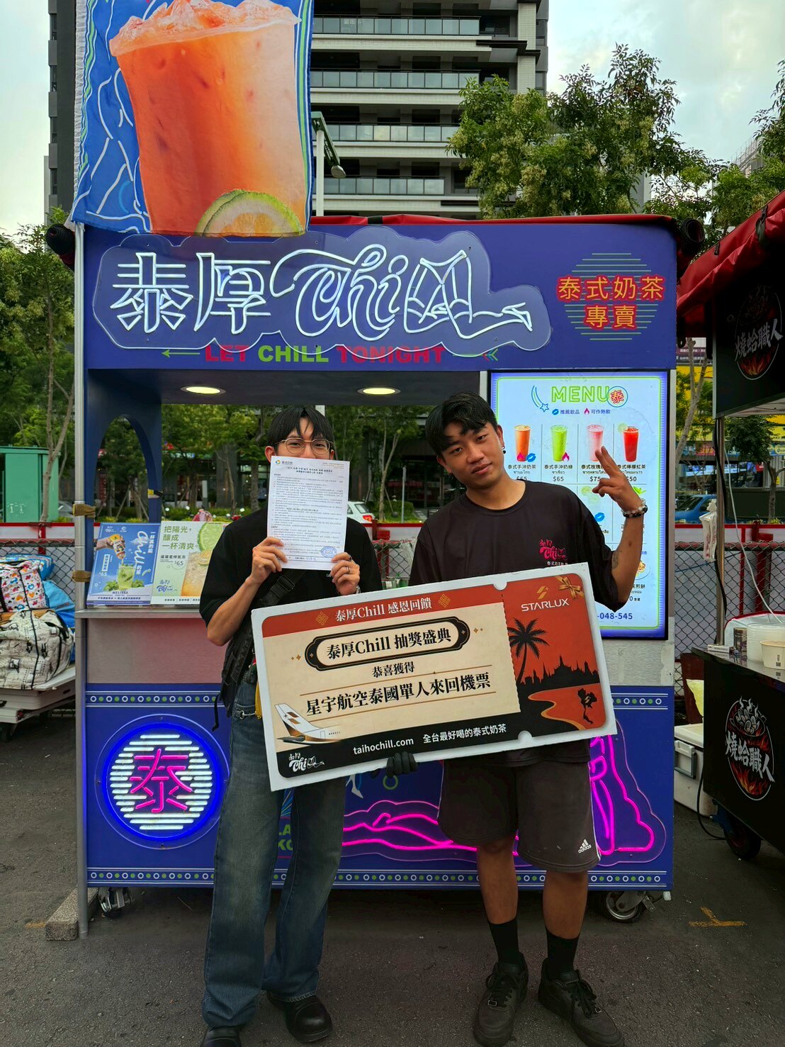 總站夜市攤車前，得主與店員手持星宇航空泰國機票獎牌與資料合影